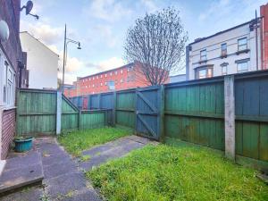ein grüner Zaun mit einem Tor und einigen Gebäuden in der Unterkunft Dalesman Apartment - 10 Minutes Walk to Manchester City Centre, Oxford Road, Chinatown, Universities in Manchester
