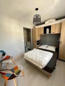 a bedroom with a large bed and a chair at Chaleureuse maisonnette avec piscine partagée in Capbreton