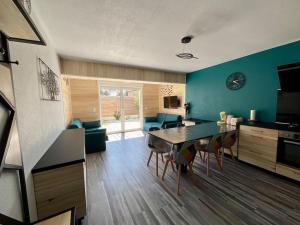 a kitchen and living room with a table and chairs at La Villa Azur - Chaleureuse maisonnette avec piscine partagée in Capbreton