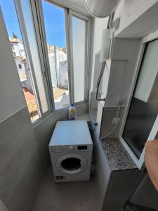 baño pequeño con lavadora y ventanas en Coqueto Apartamento, en Martos