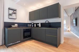 a kitchen with black cabinets and a sink at Apart Feine Zeit - Apartment Wiesele in Schönwies