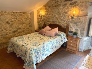 ein Schlafzimmer mit einem Bett und einer Steinmauer in der Unterkunft Vivienda Vacacional Vila Castriño en las Rias Baixas in Tarragona
