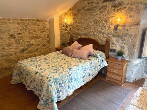 a bedroom with a bed and a stone wall at Vivienda Vacacional Vila Castriño en las Rias Baixas in Taragoña