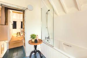 a bathroom with a shower and a small table at Inglenook Cottage, The Cotswolds in Winchcombe