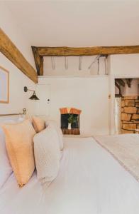 a bedroom with a white bed and a fireplace at Inglenook Cottage, The Cotswolds in Winchcombe