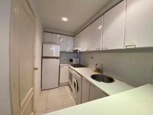 una cucina bianca con lavello e frigorifero di Apartamento a 100 metros de la playa con aire acon a Tossa de Mar Altre 15 foto