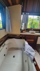 a bath tub in a bathroom with two windows at Villa Gatto Chalés - Visconde de Maua in Bocaina de Minas