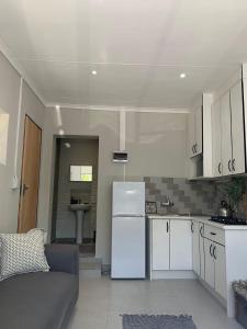 eine Küche mit weißen Schränken und einem weißen Kühlschrank in der Unterkunft 77 on Percy in Johannesburg