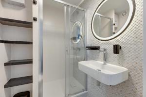 W białej łazience znajduje się umywalka i lustro. w obiekcie Petit Repit by Grand Apartments w mieście Sopot