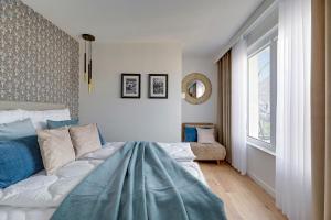 a bedroom with a bed with a blue blanket on it at Petit Repit by Grand Apartments in Sopot