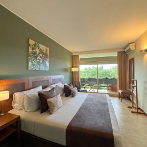 een slaapkamer met een groot bed en een balkon bij Hotel Raices Esturion in Puerto Iguazú