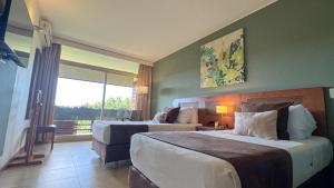 a hotel room with two beds and a window at Hotel Raices Esturion in Puerto Iguazú