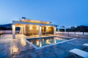 a villa with a swimming pool at night at Stone & Sea Villas in Nydri
