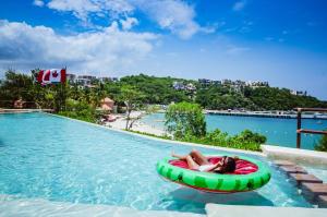 a woman laying on a raft in a pool at a resort at Nirú Ocean Suites by Binniguenda in Santa Maria Huatulco