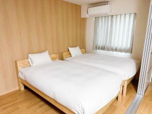 twee bedden in een kleine kamer met een raam bij RakutenSTAY x Shamaison Osaka Dekijima - Vacation STAY 12317 in Osaka