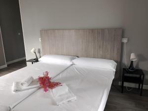 a bed with white sheets and flowers on it at Hotel Benimar in Isla