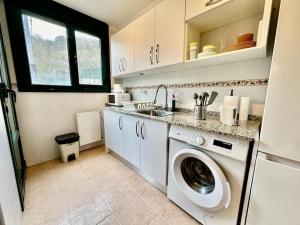 uma cozinha com uma máquina de lavar roupa e um lavatório em Encantador Piso a 150m del Tren em Pola de Lena