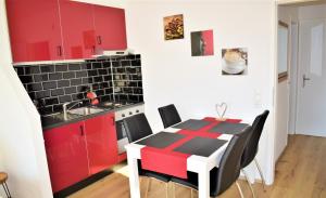 a kitchen with red cabinets and a table with chairs at Apartment d´Auszeit in Bad Goisern