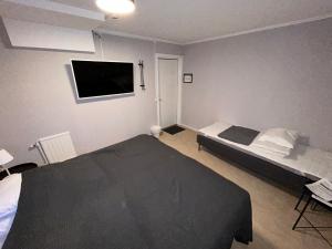 1 dormitorio con 1 cama y TV en la pared en Bakgårdens Vandrarhem, en Mariestad