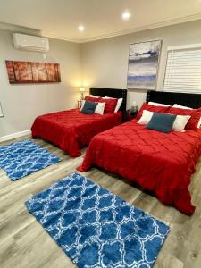 two beds in a room with red sheets and blue rugs at Sunset Dream Cottage in Los Angeles