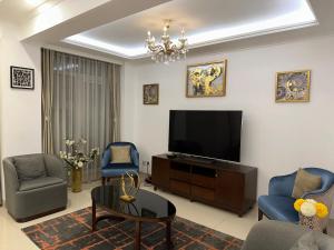 a living room with a television and two chairs and a table at SYN - Mpila in Brazzaville