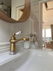 a bathroom sink with a gold faucet and a toothbrush at Noclegi Panorama in Ustrzyki Dolne
