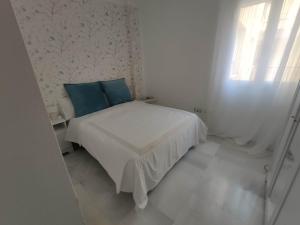 a small white bedroom with a bed with blue pillows at Prime Location! in Seville