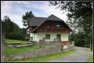 ein Haus mit einer Veranda und einer Steinmauer in der Unterkunft Apartmány Šumava in Hojsova Stráž