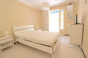 um quarto com uma cama branca e uma televisão em Antibes city center - 1 bedroom - 4 People em Antibes