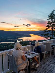 two women sitting at a table on a deck watching the sunset at Granum Gård in Fluberg