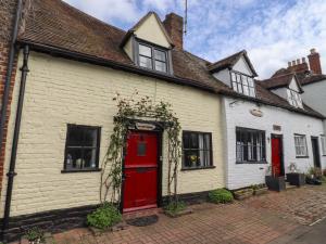 un antiguo edificio blanco con una puerta roja en Runnymede en Tewkesbury