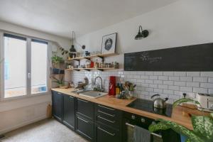 uma cozinha com armários verdes e um quadro na parede em Bright apartment in Aubervilliers em Aubervilliers