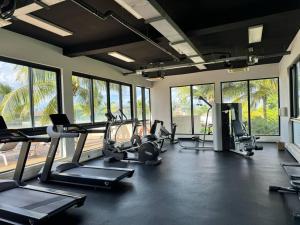 un gimnasio con cintas de correr y elípticas en una habitación con ventanas en Entire Luxury Azuri Apartment TB, en Roches Noires