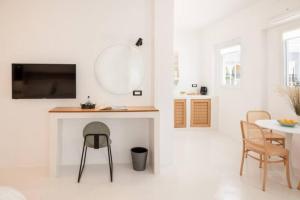 een witte woonkamer met een tafel en een kruk bij Piccole Case in Kamari