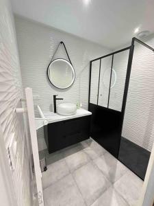 een badkamer met een wastafel en een spiegel bij Maison vue mer chez Aline in Digosville