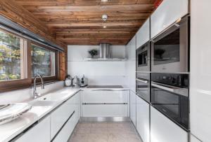 a kitchen with white cabinets and a wooden ceiling at Résidence Eden - Chalets pour 10 Personnes 754 in Courchevel