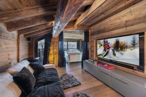 a living room with a couch and a large tv at Résidence Eden - Chalets pour 10 Personnes 754 in Courchevel