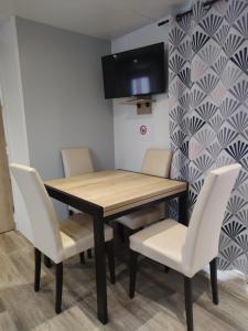 a dining room table with white chairs and a television at Mobil home 3 chambres Accès direct plage 4 Etoiles in Canet-en-Roussillon
