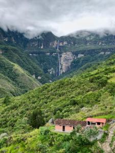 una casa al lado de una montaña con una cascada en La Casa de Mario - Gocta, en Cocachimba