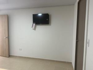 Habitación con TV en una pared blanca en Leonor’s Guest House, en Providencia