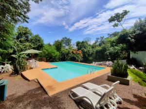 una piscina en un patio con sillas alrededor en Raices Amambai Lodges en Puerto Iguazú
