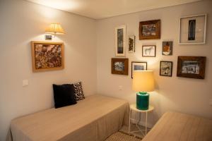 two beds in a room with a lamp and pictures on the wall at To see the sea apartment in Sesimbra