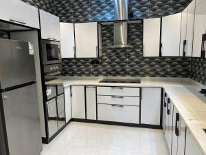 una cocina con armarios blancos y electrodomésticos en blanco y negro en Fhr-105 en Al-Salam