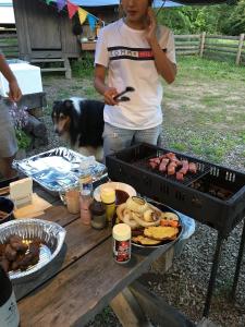Una donna in piedi accanto a un barbecue con un cane di Camp inn Kiyosato GRANDEUR - Vacation STAY 42080v a Hokuto