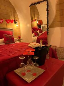 Tama67 suite في أوستوني: غرفة بسرير احمر مع وجود كأسين على طاولة