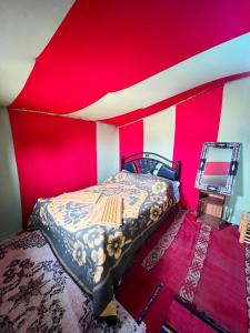 a bed in a room with a red wall at Camp Mbark authentic in Mhamid