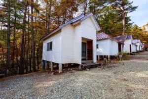 una pequeña casa blanca en medio de un bosque en Shinei Kiyosato Campsite - Vacation STAY 42245v, en Hokuto