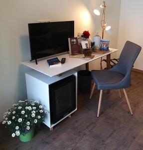 a desk with a computer and a chair and a television at DOMS Gästehaus in Frauenkirchen