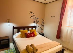 a bedroom with a bed with yellow and red pillows at Casa de Lis Hotel & Tourist Info Centre in Turrialba