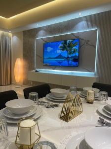 einen Tisch mit weißen Tellern und einen TV an der Wand in der Unterkunft شقة فندقية ALzorah Ajman - الزوراء عجمان in Ajman 
